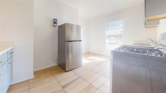 kitchen featuring stainless steel fridge, light tile patterned floors, and sink