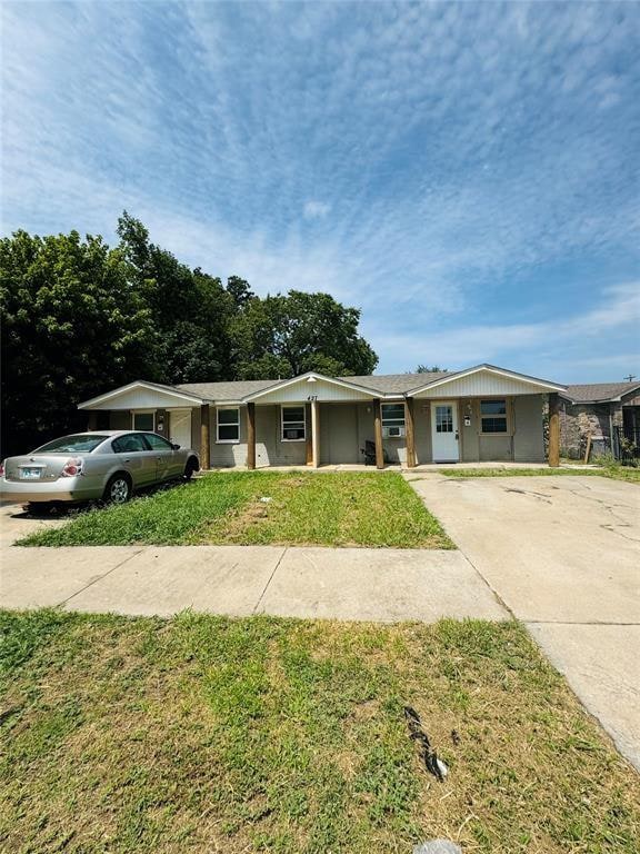 view of front of house with concrete driveway, covered porch, and a front lawn