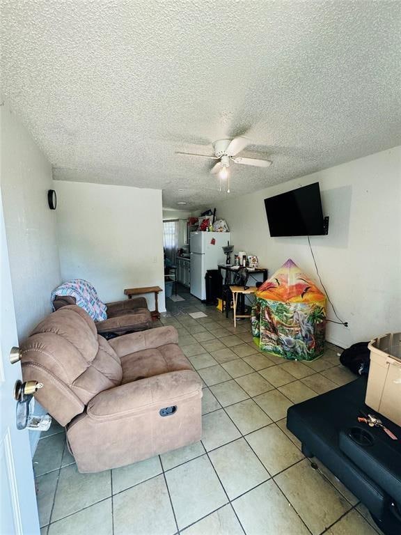 living room with light tile patterned floors, a textured ceiling, and a ceiling fan