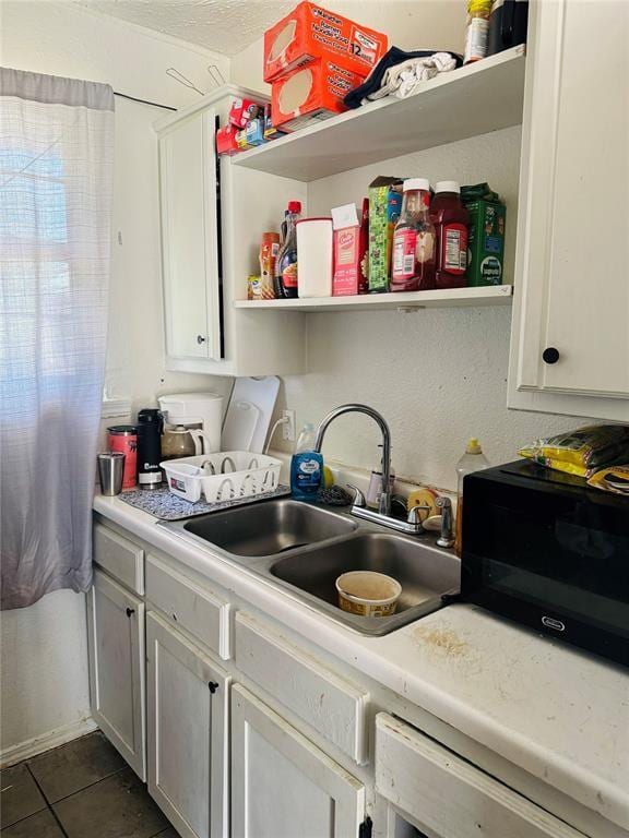 kitchen featuring a textured ceiling, dark tile patterned floors, a sink, light countertops, and open shelves