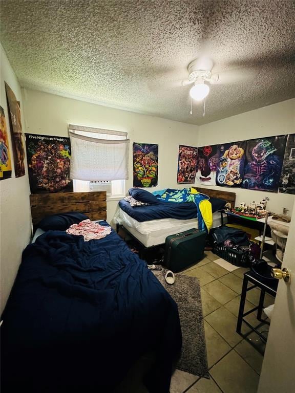 bedroom featuring a ceiling fan, light tile patterned flooring, and a textured ceiling