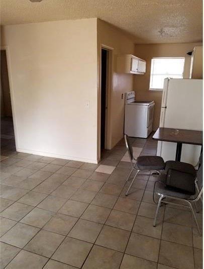 kitchen featuring independent washer and dryer, a textured ceiling, and freestanding refrigerator