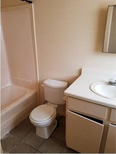 bathroom featuring toilet,  shower combination, vanity, and tile patterned floors