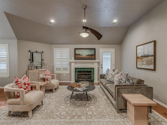 living room with visible vents, light wood-style flooring, vaulted ceiling, ceiling fan, and baseboards