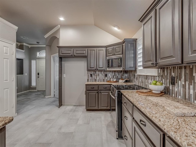 kitchen featuring light stone countertops, black microwave, backsplash, and electric stove