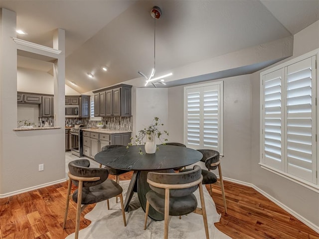 dining room featuring baseboards, vaulted ceiling, and wood finished floors