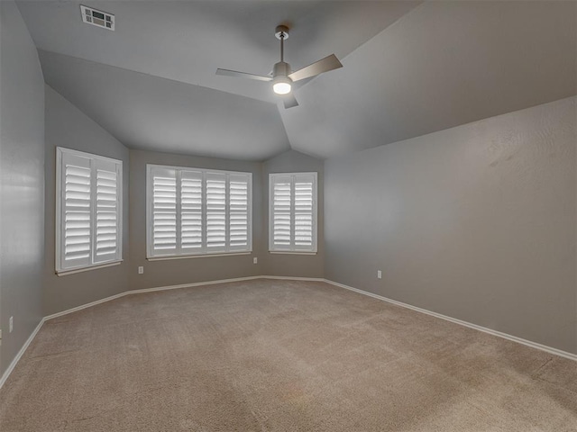 unfurnished room with lofted ceiling, light colored carpet, a ceiling fan, baseboards, and visible vents