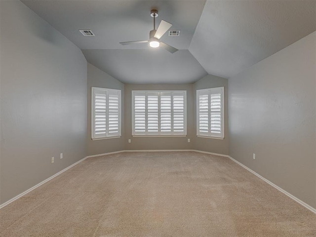 spare room with lofted ceiling, a wealth of natural light, visible vents, and a ceiling fan