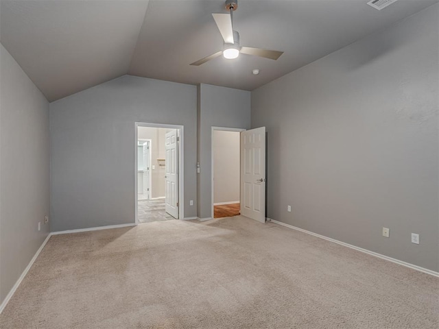 unfurnished bedroom featuring lofted ceiling, baseboards, ensuite bath, and light colored carpet