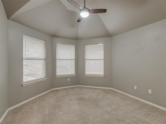 empty room with a healthy amount of sunlight, light colored carpet, vaulted ceiling, and ceiling fan