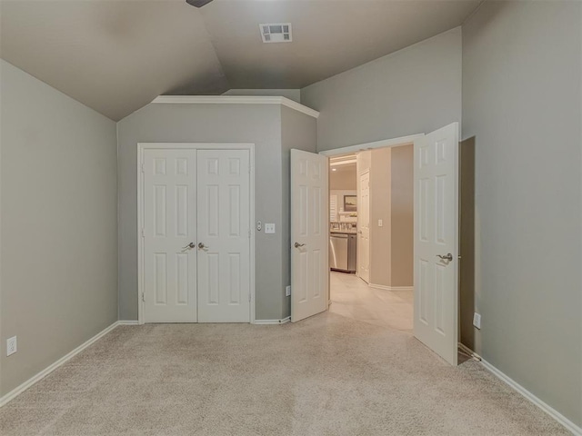 unfurnished bedroom with light carpet, visible vents, baseboards, vaulted ceiling, and a closet