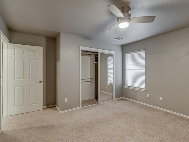 unfurnished bedroom featuring baseboards, visible vents, a closet, and light colored carpet