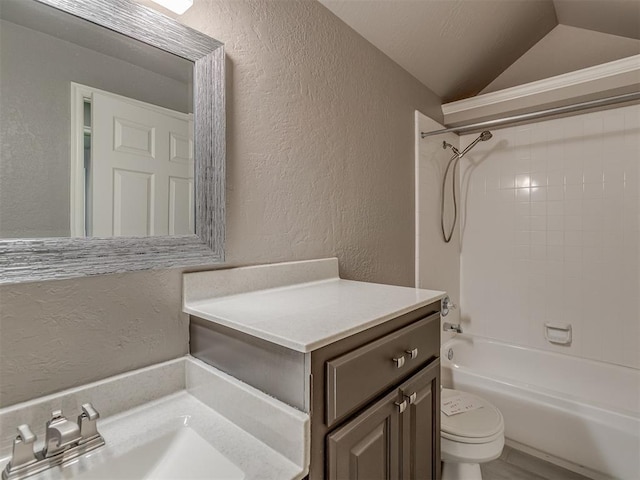 bathroom featuring a textured wall, toilet, lofted ceiling, shower / tub combination, and vanity