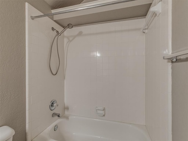 full bathroom with washtub / shower combination, a textured wall, and toilet