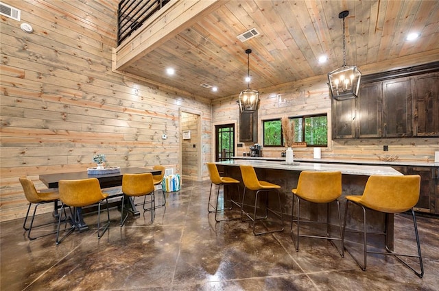 kitchen featuring wooden walls, dark brown cabinets, a center island, and hanging light fixtures