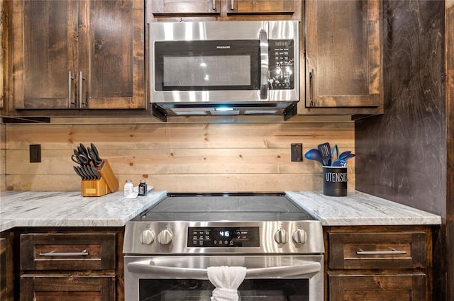 kitchen featuring light stone counters, dark brown cabinetry, and appliances with stainless steel finishes