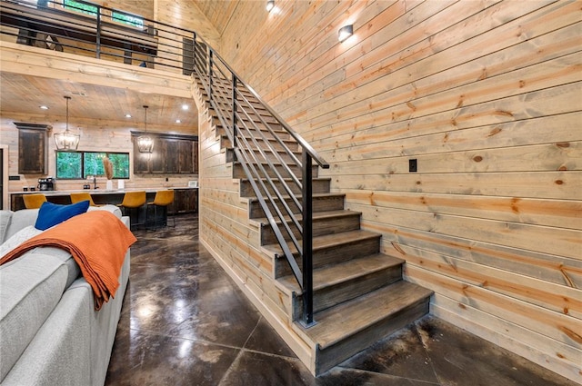 stairs with wood ceiling, a high ceiling, and wooden walls