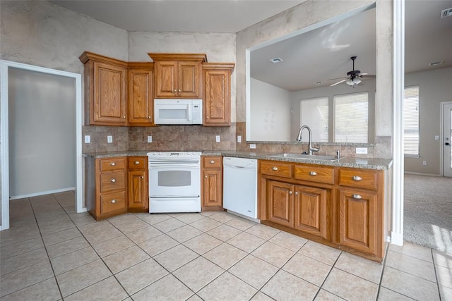 kitchen featuring white appliances, sink, ceiling fan, light tile patterned floors, and light stone counters