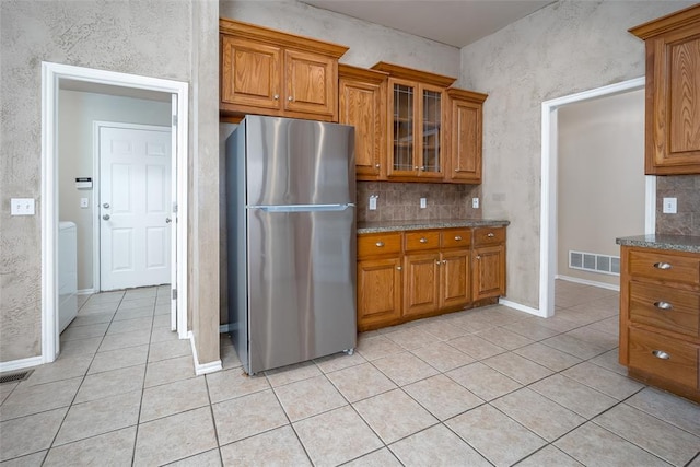 kitchen with stainless steel fridge, light tile patterned floors, and light stone counters