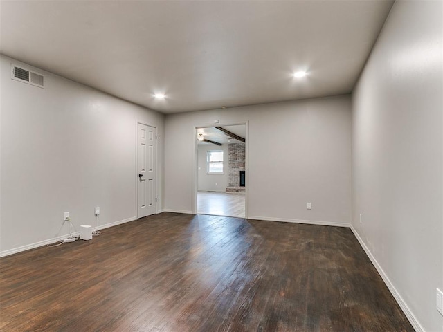 spare room with dark hardwood / wood-style flooring and a fireplace