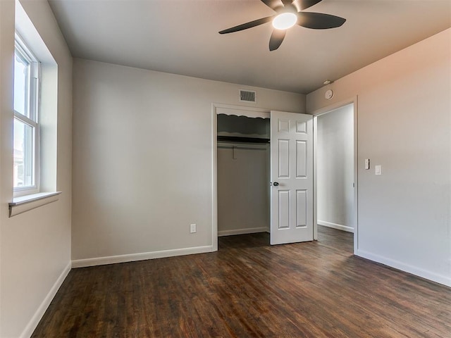 unfurnished bedroom with multiple windows, ceiling fan, and dark hardwood / wood-style flooring