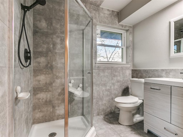 bathroom featuring vanity, tile patterned floors, toilet, tile walls, and an enclosed shower