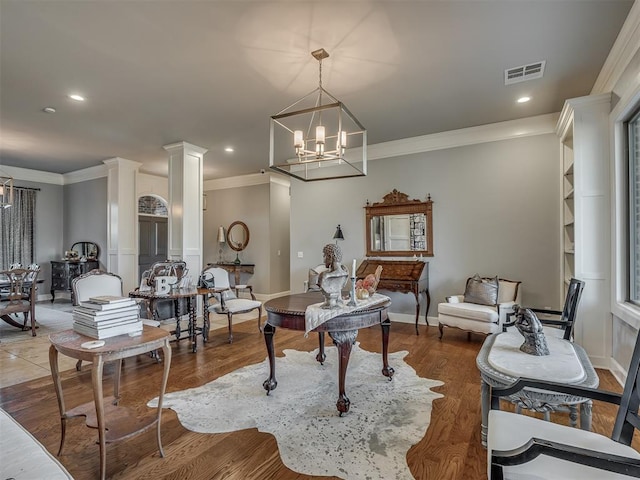 interior space featuring decorative columns, a chandelier, wood-type flooring, and ornamental molding