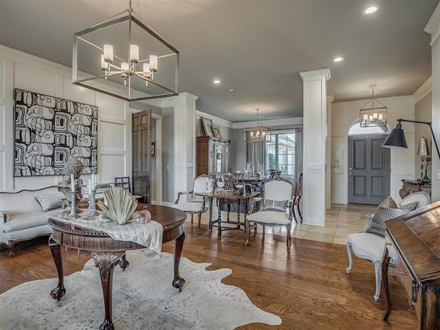 living room with a chandelier, ornate columns, ornamental molding, and light hardwood / wood-style flooring