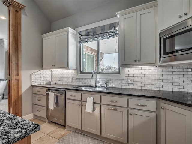 kitchen with backsplash, sink, light tile patterned floors, appliances with stainless steel finishes, and decorative columns