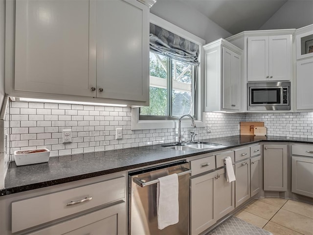 kitchen featuring sink, vaulted ceiling, decorative backsplash, appliances with stainless steel finishes, and light tile patterned flooring