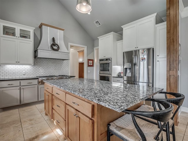 kitchen featuring a kitchen island, white cabinetry, appliances with stainless steel finishes, and dark stone counters