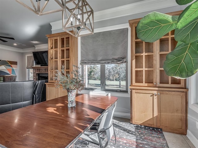 dining space featuring a fireplace, light tile patterned floors, ceiling fan, and ornamental molding