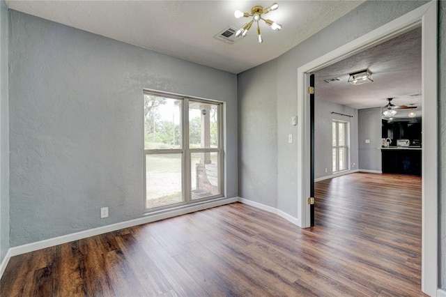 unfurnished room with wood-type flooring and ceiling fan with notable chandelier