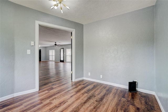 spare room with hardwood / wood-style floors, a textured ceiling, and an inviting chandelier