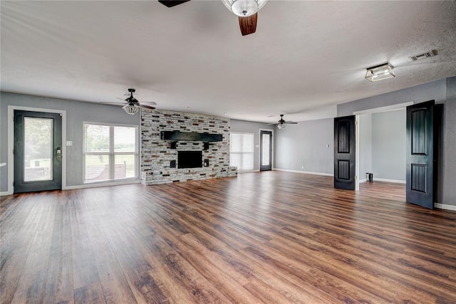 unfurnished living room featuring ceiling fan, dark hardwood / wood-style flooring, a textured ceiling, and a brick fireplace