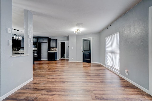 unfurnished living room with dark hardwood / wood-style flooring and a chandelier