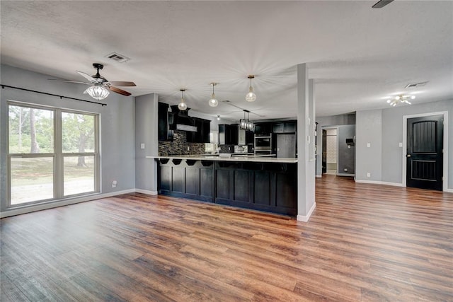 kitchen with kitchen peninsula, tasteful backsplash, a textured ceiling, ceiling fan, and dark wood-type flooring