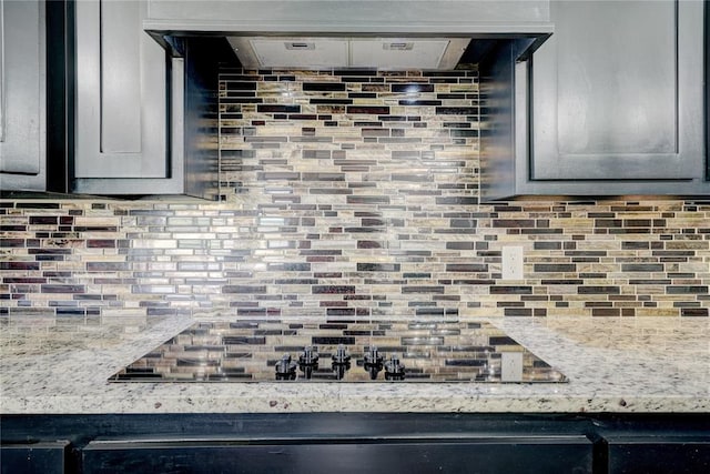 kitchen with decorative backsplash, gray cabinets, and light stone countertops