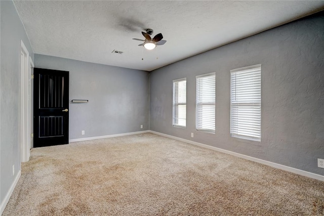 carpeted spare room featuring a textured ceiling and ceiling fan