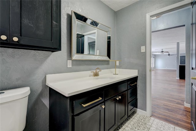 bathroom featuring ceiling fan, toilet, vanity, and hardwood / wood-style flooring