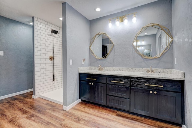 bathroom featuring hardwood / wood-style floors, vanity, and a tile shower