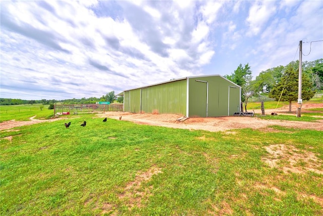 view of outbuilding featuring a lawn and a rural view