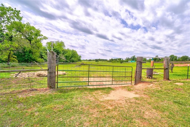 view of gate featuring a lawn and a rural view