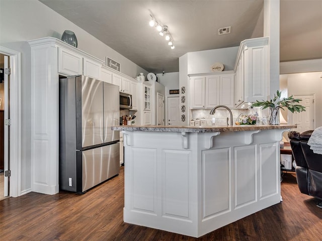 kitchen with white cabinets, backsplash, stainless steel appliances, and dark hardwood / wood-style floors