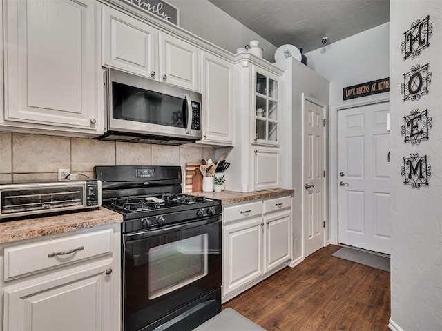 kitchen featuring white cabinets, black gas range, dark hardwood / wood-style floors, and decorative backsplash