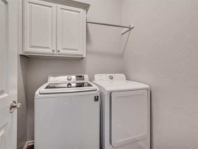 clothes washing area featuring washer and clothes dryer and cabinets