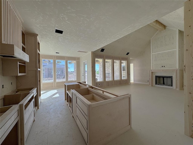 kitchen with a textured ceiling, a center island, and vaulted ceiling with beams