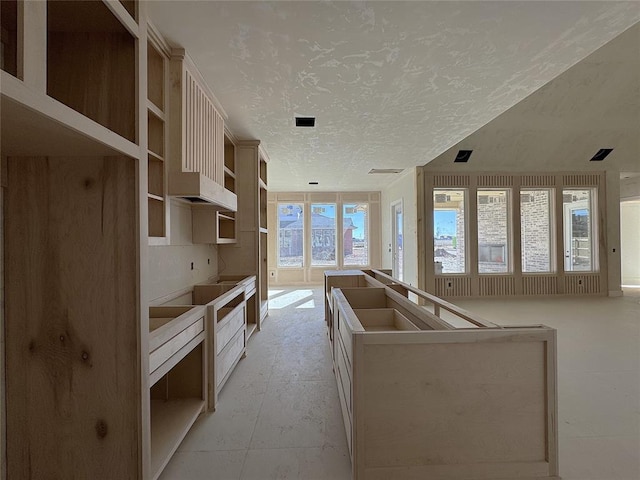 kitchen with a textured ceiling, a center island, and a healthy amount of sunlight