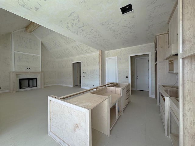 kitchen featuring kitchen peninsula, vaulted ceiling with beams, light brown cabinetry, and a fireplace