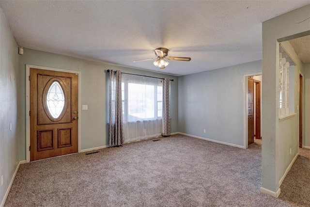 entrance foyer featuring light carpet, a textured ceiling, and ceiling fan